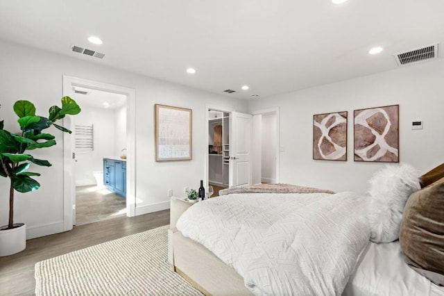 bedroom featuring hardwood / wood-style flooring, a walk in closet, and ensuite bath