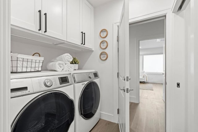 laundry area featuring cabinets, light hardwood / wood-style flooring, and independent washer and dryer