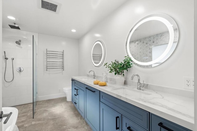 bathroom featuring vanity, toilet, and a tile shower