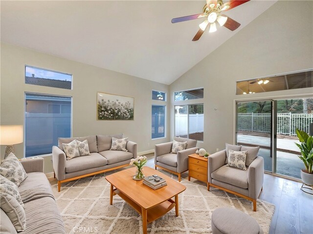 living room with ceiling fan, high vaulted ceiling, light hardwood / wood-style floors, and a healthy amount of sunlight