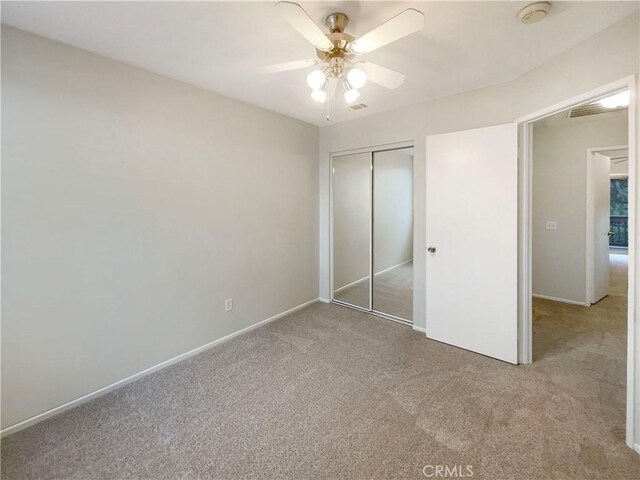 unfurnished bedroom with ceiling fan, a closet, and light carpet