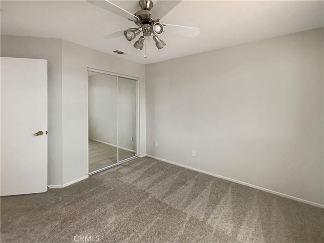 unfurnished bedroom featuring ceiling fan, a closet, and dark colored carpet