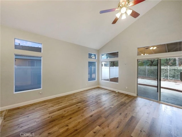 unfurnished room with hardwood / wood-style floors, ceiling fan, a wealth of natural light, and high vaulted ceiling