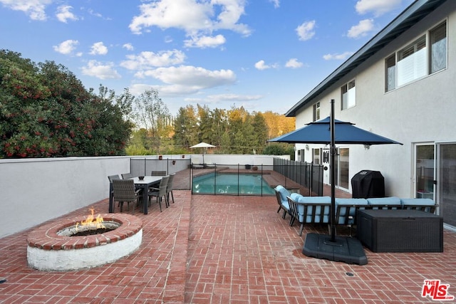 view of patio / terrace featuring a fenced in pool, area for grilling, and a fire pit