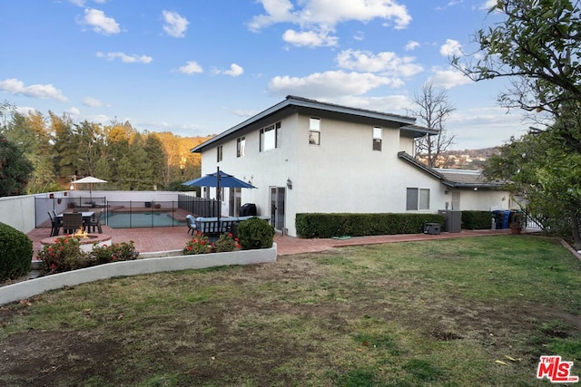 back of house with central AC, a patio area, and a lawn