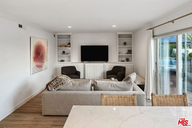 living room featuring crown molding, wood-type flooring, and built in shelves