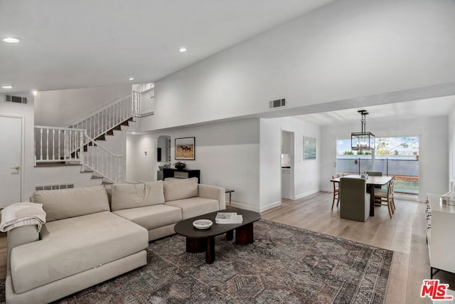 living room featuring wood-type flooring, an inviting chandelier, and high vaulted ceiling