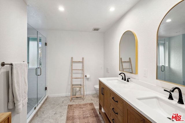 bathroom featuring vanity, a shower with shower door, and toilet