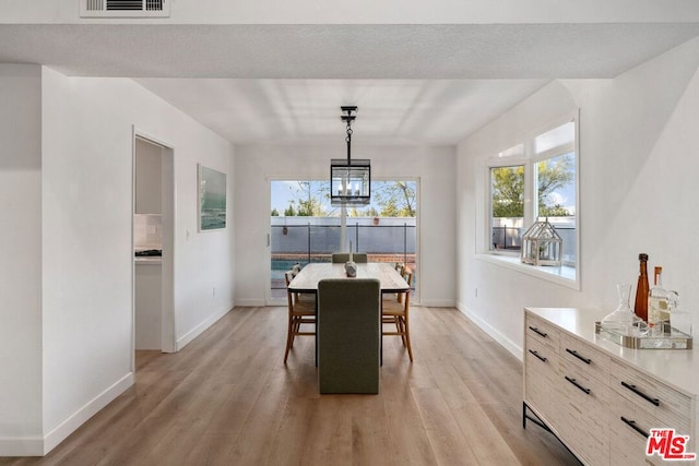 dining area with a notable chandelier and light hardwood / wood-style flooring