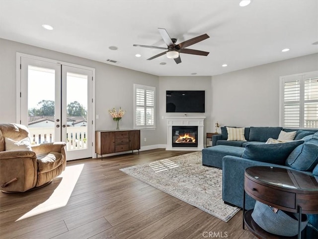 living room with wood-type flooring, french doors, and ceiling fan