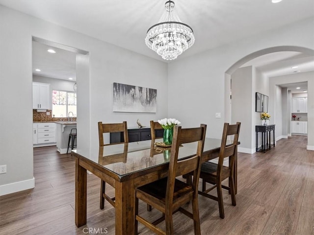 dining room featuring sink, dark wood-type flooring, and a chandelier