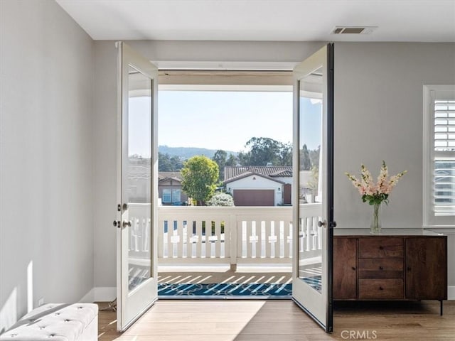 bedroom with multiple windows, wood-type flooring, and french doors