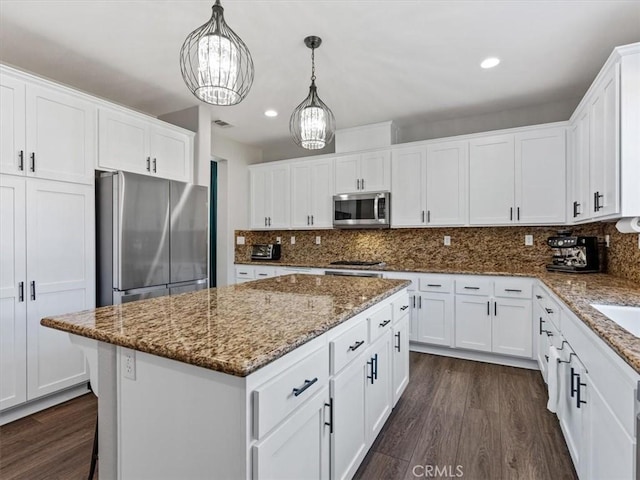 kitchen featuring pendant lighting, stainless steel appliances, white cabinets, and a kitchen island