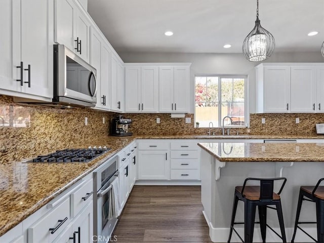 kitchen featuring pendant lighting, stainless steel appliances, sink, and white cabinets