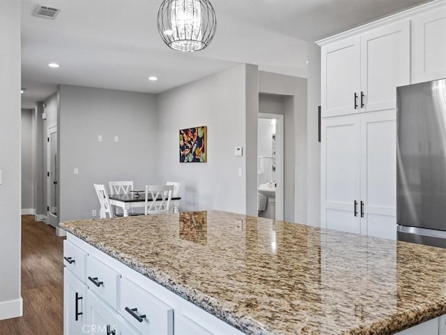 kitchen with white cabinetry, dark hardwood / wood-style flooring, stainless steel refrigerator, and light stone counters