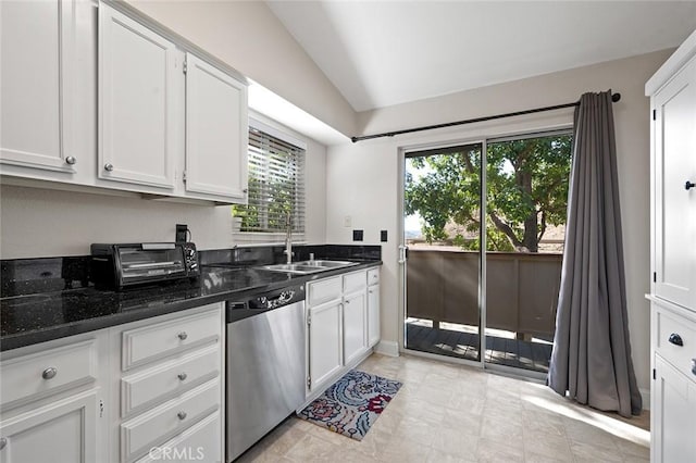 kitchen featuring vaulted ceiling, dishwasher, sink, dark stone countertops, and white cabinets