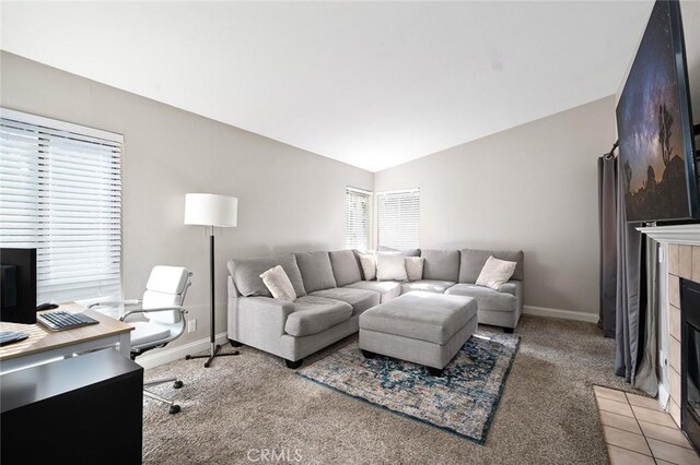 carpeted living room featuring a tiled fireplace and vaulted ceiling