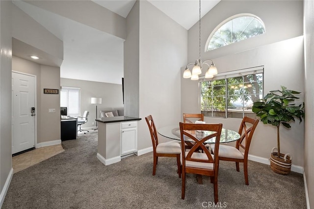 carpeted dining space with high vaulted ceiling and an inviting chandelier