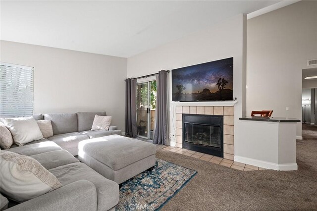 living room with a tile fireplace and light colored carpet