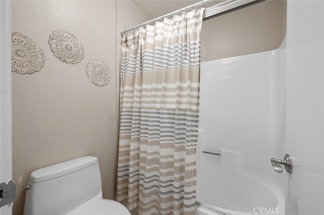 bathroom featuring a shower with shower curtain and toilet