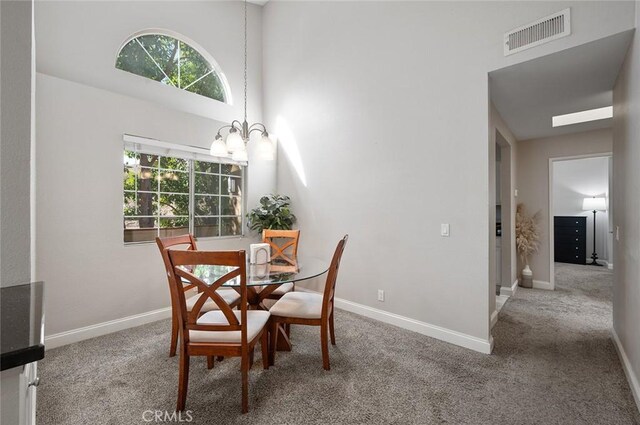 dining space featuring a chandelier, carpet floors, and a high ceiling