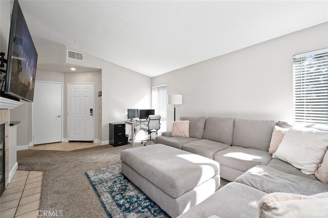 living room with a fireplace, vaulted ceiling, and light colored carpet