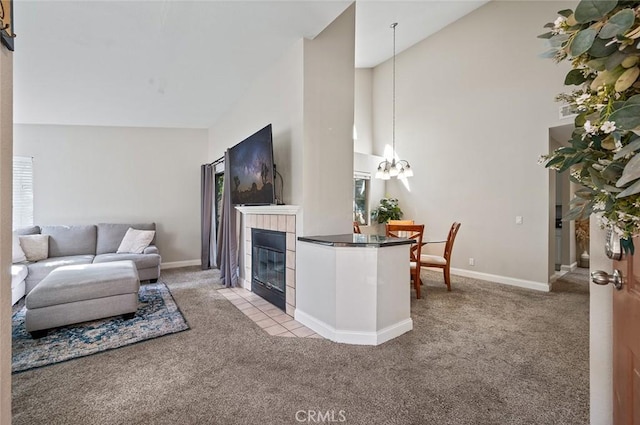 living room with a chandelier, light colored carpet, a tiled fireplace, and high vaulted ceiling