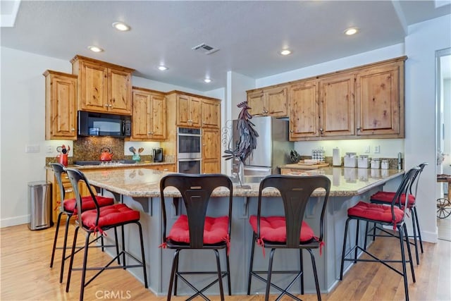 kitchen with light stone countertops, a center island, a breakfast bar area, and black appliances