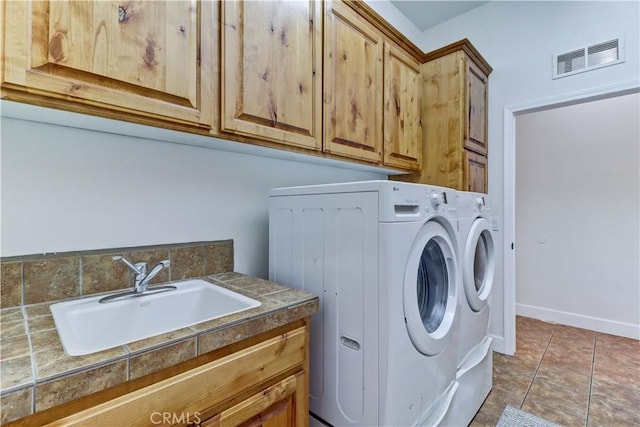 laundry room with tile patterned flooring, sink, cabinets, and washing machine and clothes dryer