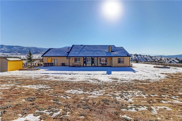 snow covered back of property featuring a mountain view