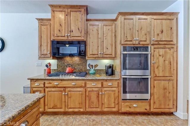 kitchen featuring light tile patterned flooring, appliances with stainless steel finishes, light stone counters, and decorative backsplash