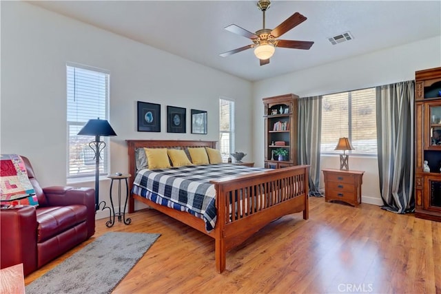 bedroom with multiple windows, hardwood / wood-style floors, and ceiling fan