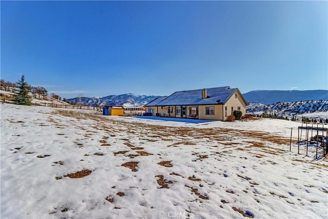 snow covered back of property with a mountain view