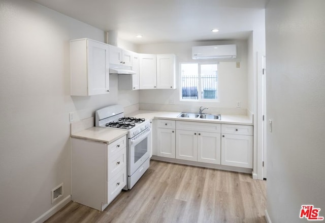 kitchen featuring sink, white gas stove, white cabinetry, a wall mounted AC, and light wood-type flooring