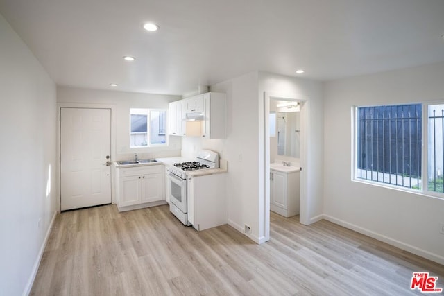 kitchen featuring white cabinetry, sink, gas range gas stove, and a healthy amount of sunlight