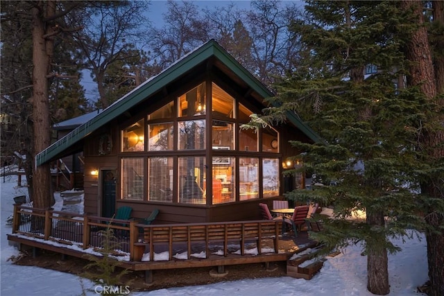 snow covered back of property featuring a deck