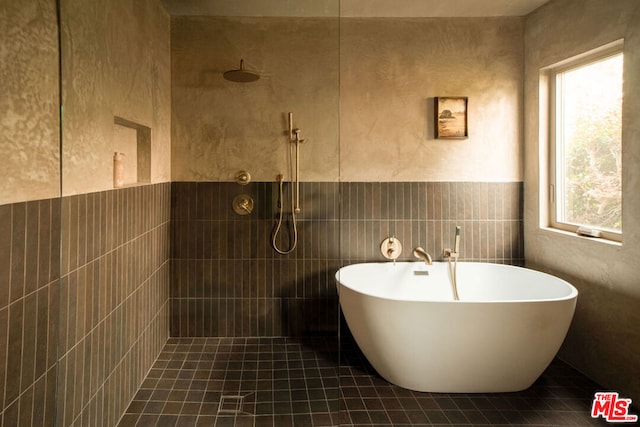 bathroom featuring plus walk in shower, tile patterned flooring, and tile walls