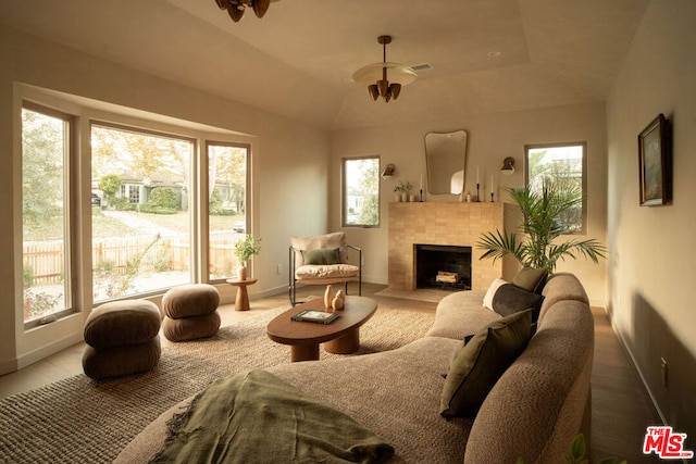 living room featuring a tray ceiling, a tile fireplace, and a wealth of natural light