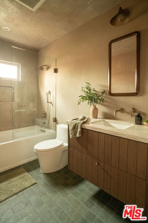 full bathroom with tiled shower / bath combo, vanity, and toilet