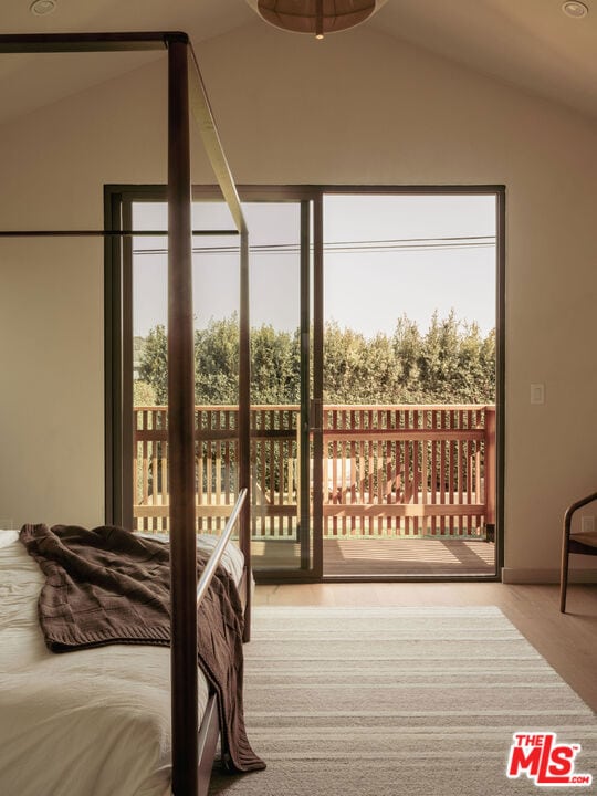 bedroom featuring lofted ceiling, access to exterior, and light wood-type flooring