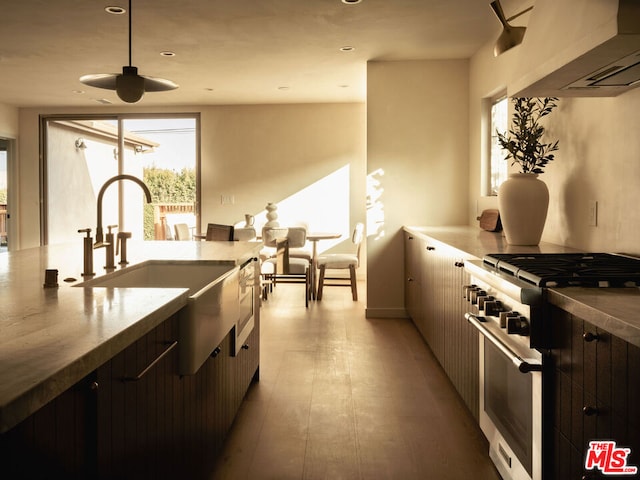 kitchen with stainless steel range, wall chimney exhaust hood, sink, and light wood-type flooring