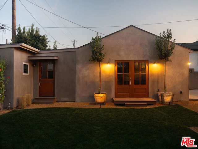 back house at dusk with a lawn