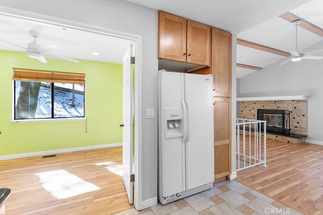 kitchen featuring vaulted ceiling, light hardwood / wood-style flooring, ceiling fan, a fireplace, and white refrigerator with ice dispenser