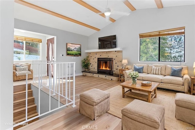 living room featuring lofted ceiling with beams, ceiling fan, a fireplace, and light hardwood / wood-style flooring