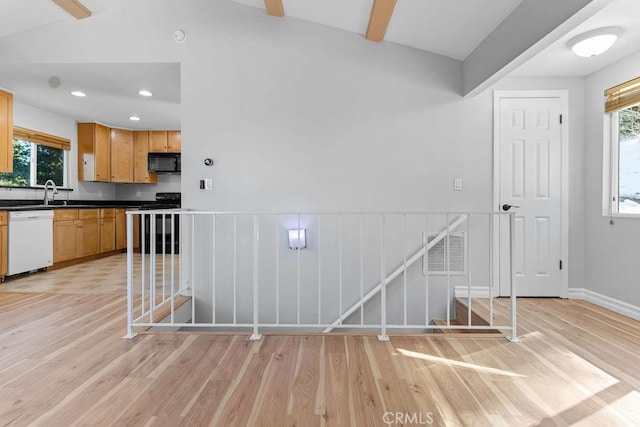 kitchen with dishwasher, vaulted ceiling with beams, sink, stove, and light wood-type flooring