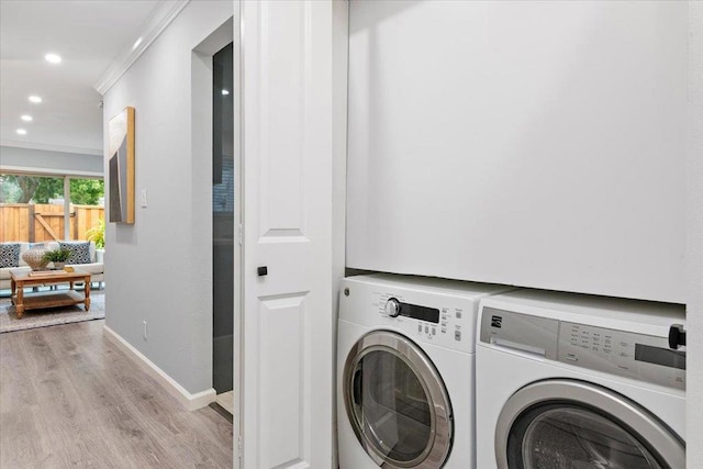 laundry room with ornamental molding, independent washer and dryer, and light hardwood / wood-style floors