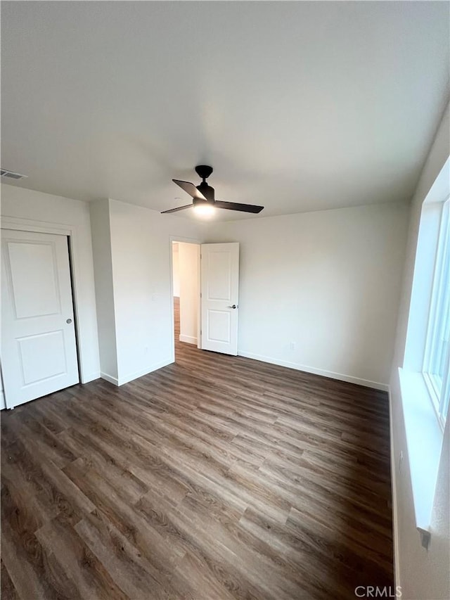 unfurnished bedroom with a closet, dark hardwood / wood-style floors, and ceiling fan