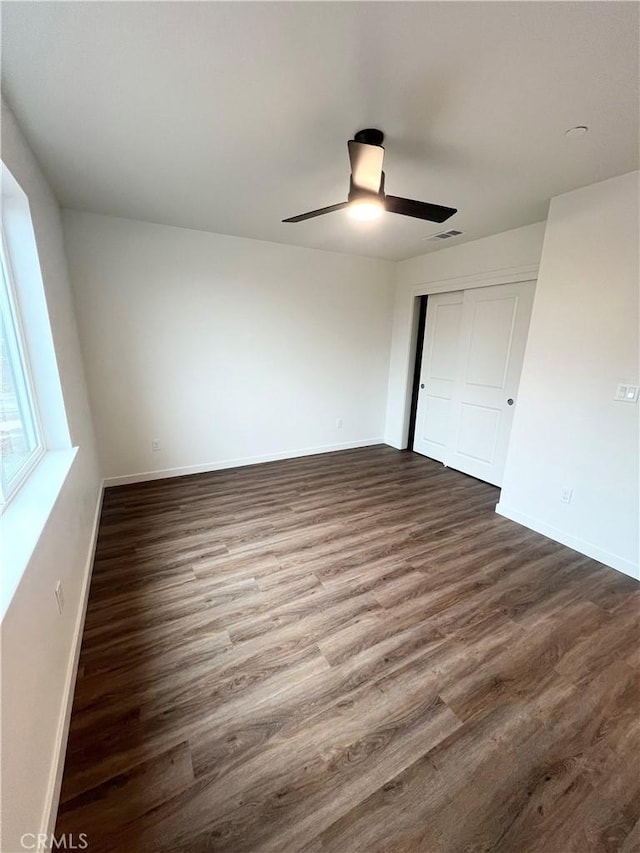 unfurnished bedroom featuring ceiling fan, dark hardwood / wood-style floors, and a closet