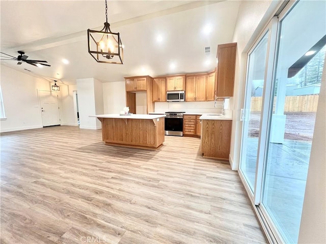 kitchen featuring hanging light fixtures, a center island, light hardwood / wood-style floors, stainless steel appliances, and plenty of natural light