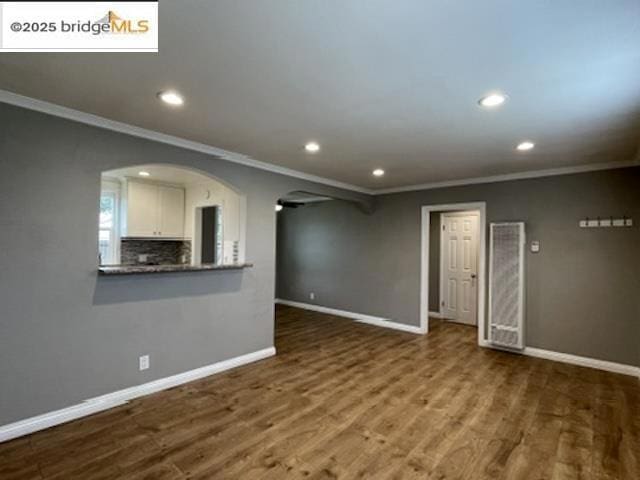 unfurnished living room with ornamental molding and wood-type flooring